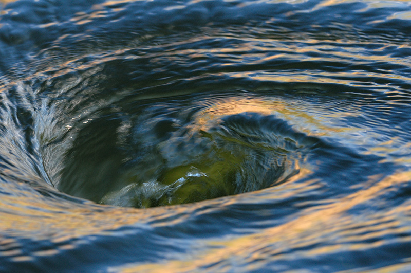 small whirlpool on the Lower Owens River with sunset light swirling into the vortex